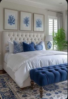 a bedroom with blue and white decor on the wall above the bed, along with an ottoman