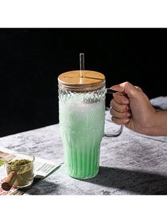 a person holding a green cup on top of a table