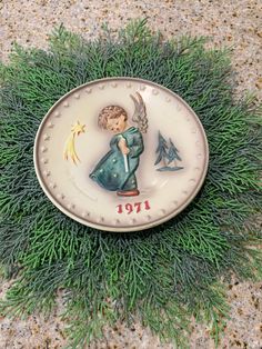 an angel figurine sitting on top of a plate with green grass around it