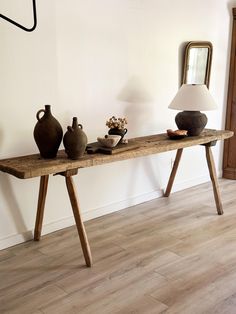 a wooden table with two vases on it and a lamp sitting on top of it