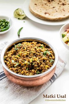 a bowl filled with rice and vegetables next to some pita bread on a table