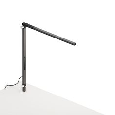 a desk lamp that is on top of a white table with a black cord attached to it