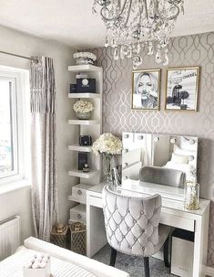 a white desk with a chandelier hanging from it's ceiling and some pictures on the wall