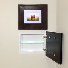 two framed pictures hang on the wall next to an open door with a shelf below