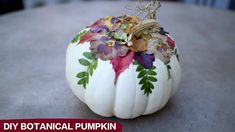 a white pumpkin decorated with flowers and leaves