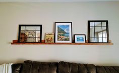 a living room filled with furniture and framed pictures on top of a wooden shelf above a couch