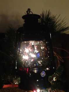 a lighted lantern sitting on top of a christmas tree