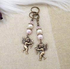 these new handmade earrings were created by me with small antiqued brass winged cherub angel charms.  They are as cute as can be with their bow and arrows!  The backs are hollow on these charms.  Above I added top quality crystal cored pearls in both soft pink and cream colors topped with smaller light pink crystal beads.  Total length including the brass lever back ear wires is 2 1/2 inches.  To see more of my designs please click here:  www.etsy.com/shop/hhjewelrydesigns Pink Pearl Jewelry, Light Pink Crystal, Angel Charms, Cherub Angel, Angel Earrings, Handcrafted Artisan Jewelry, Pink Pearl, Pink Crystal, Handmade Earrings