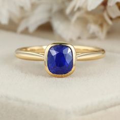 Indulge in luxury with our 14K Yellow Gold Cushion Cut Blue Sapphire Ring for Women. This captivating piece combines opulence and sophistication, featuring a mesmerizing blue sapphire gemstone elegantly set in lustrous yellow gold. Elegant Gold Sapphire Ring With Cushion Cut, Timeless Sapphire Ring With Bezel Setting, Timeless Polished Sapphire Ring, Timeless Sapphire Ring With Birthstone, Timeless Sapphire Birthstone Ring, Blue Sapphire Ring With Bezel Setting, Elegant Sapphire Ring With Tanzanite And Polished Finish, Gold Sapphire Ring With Cushion Cut, Gold Cushion Cut Sapphire Ring