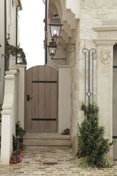 an entry way to a house with a light on and flowers growing in the planters