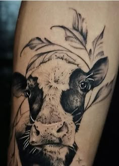 a black and white photo of a cow's head with leaves around it on the thigh