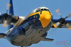 a blue and yellow airplane flying in the sky with propellers on it's wings