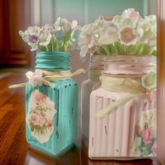 two jars with flowers in them sitting on a table