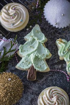 christmas cookies decorated with icing and sprinkles on a cooling rack next to other decorations