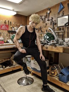 a young man sitting on top of a stool in a room filled with clutter