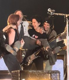 a group of people standing on top of a stage with guitars and microphones in their hands