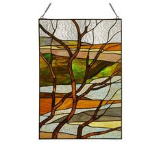 a stained glass window hanging on the side of a wall with a tree in it