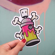 a hand holding up a sticker with pink and yellow paint on it