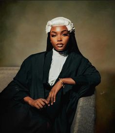 a woman sitting on top of a couch wearing a black suit