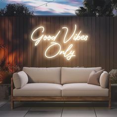 a couch sitting in front of a wooden wall with the words good vibes only on it