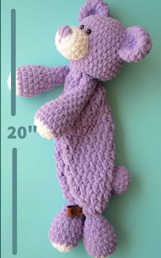 a crocheted purple teddy bear laying on top of a blue background with the number 20 in front of it