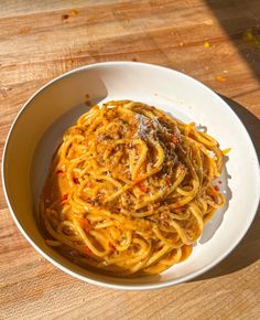 a white bowl filled with pasta on top of a wooden table