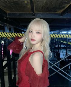 a woman with long blonde hair wearing headphones and red dress standing in front of stairs