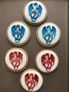 four cookies decorated with blue and red icing are arranged in the shape of a dragon