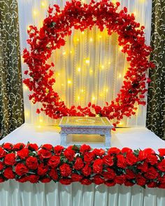 a table topped with red flowers and a heart - shaped wreath on top of it