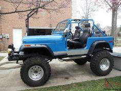 a blue jeep is parked in front of a brick building with its doors open and the driver's seat up