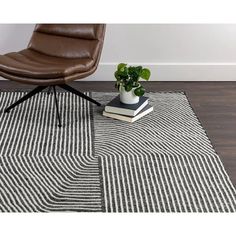 a chair sitting on top of a wooden floor next to a rug and potted plant