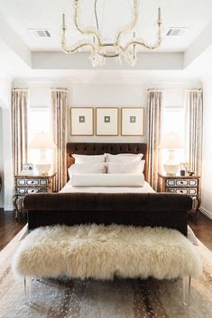 a bedroom with a bed, two nightstands and a chandelier hanging from the ceiling