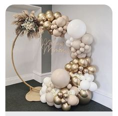 the balloon arch is decorated with gold and white balloons, feathers, and some flowers