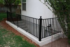 a black iron fence next to a white house