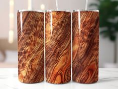 three tumblers with wooden designs on them sitting on a table