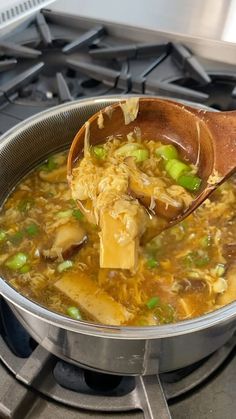 a wooden spoon full of soup on top of a stove