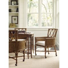 two wicker chairs and a table in front of a window with open shutters