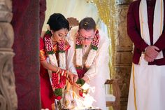 a man and woman cutting into a cake on top of a table next to each other