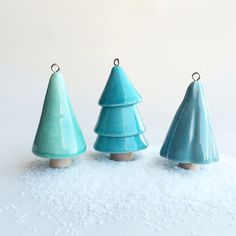 three small ceramic christmas trees sitting in the snow