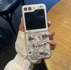 a person holding up a cell phone with cartoon characters on the front and back cover