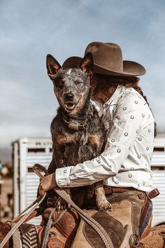 a woman riding on the back of a brown horse with a dog in her lap