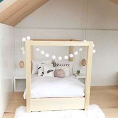 a white bed sitting in the middle of a bedroom under a slanted roof with lights