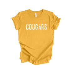 Show your school spirit with our exclusive Cougars T-Shirt, designed for ultimate comfort and style. Whether you're cheering from the stands, attending a school event, or just wanting to express your pride, this tee is the perfect choice.  This Cougars T-Shirt is more than just apparel; it's a symbol of unity, passion, and pride. Every time you wear it, you're not only supporting your team but also joining a community of dedicated fans who believe in the spirit of the Cougars. Ideal for students, alumni, parents, and fans who want to show their support in style. Why You'll Love It: *Comfort Beyond Compare: Soft fabric that feels great against your skin, making it a go-to piece in your wardrobe. *Versatile Style: Perfect for game days, casual outings, or as a gift for any Cougars fan. *Unis Collegiate Style School T-shirt With Screen Print, School Spirit T-shirt For Game Day, Collegiate T-shirt With University Logo For Game Day, School Spirit Tops For Football Season, Collegiate Letter Print T-shirt For School, College T-shirt With School Spirit, Casual T-shirt For School Football Season, College Football Season School Spirit T-shirt, Pre-shrunk Varsity T-shirt For Fan Gear