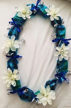 a blue and white flowered necklace with bells on the bottom is laying on a bed