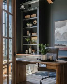 a room with a desk, chair and bookshelf next to a glass door