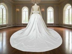 a white wedding dress is on display in a room with windows and chandelier