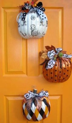 three pumpkins are hanging on the front door and one is decorated with black and white stripes