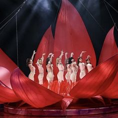 a group of women standing on top of a red boat in front of a crowd