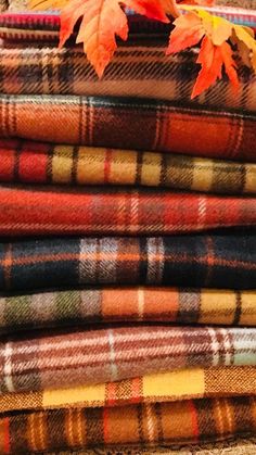 a stack of plaid fabric with autumn leaves on top and bottom, all in different colors