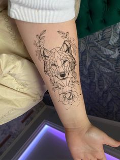 a woman's arm with a tattoo of a wolf and flowers on the wrist